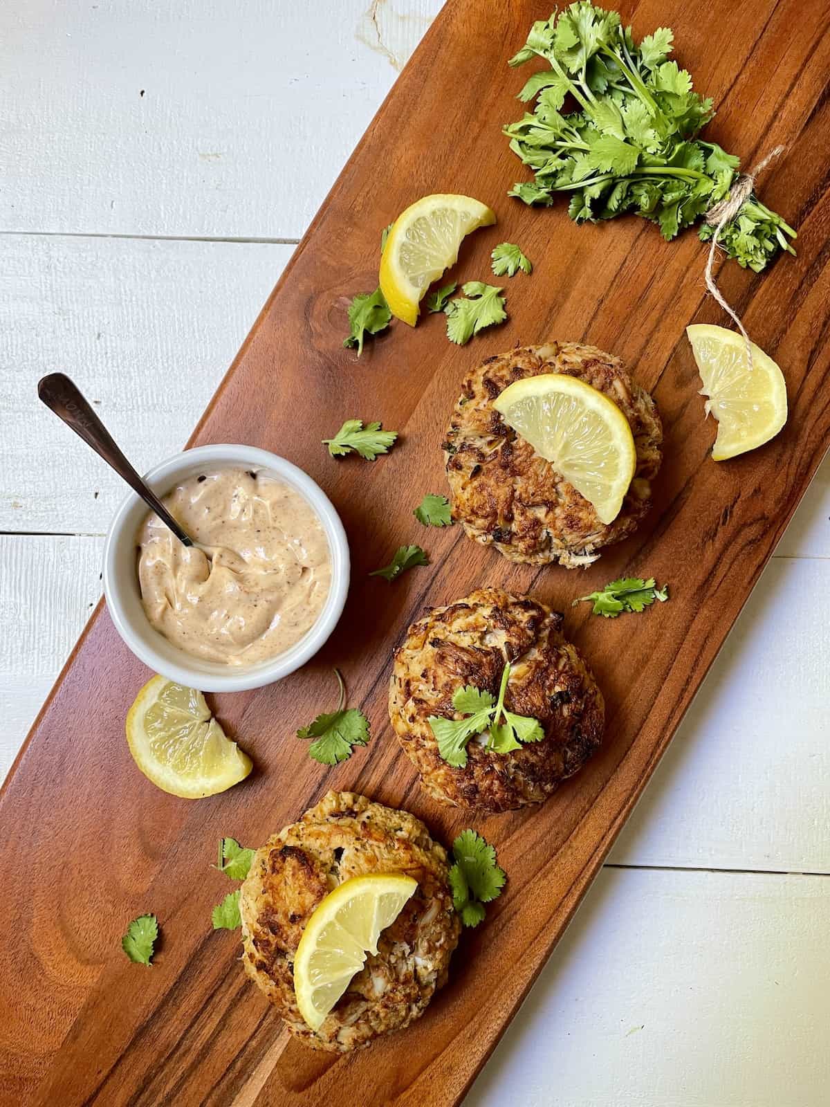 Crab cakes on a wood board with lemon and parsley.
