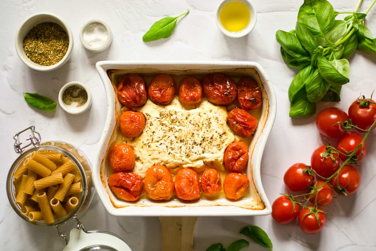 Feta with tomatoes baked in a white casserole dish.