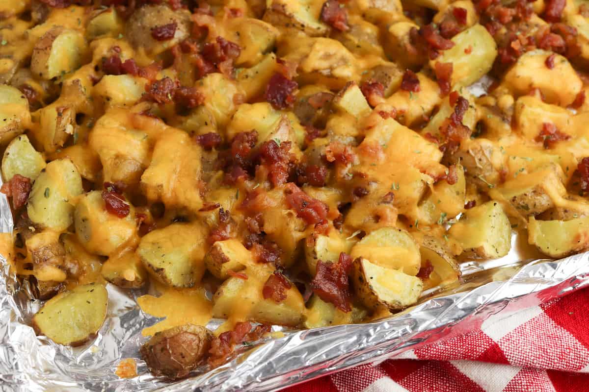 Roasted potatoes with melted cheese and bacon on a sheet pan.