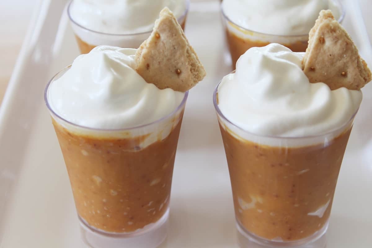 Pumpkin pudding in shot glasses topped with whipped cream.