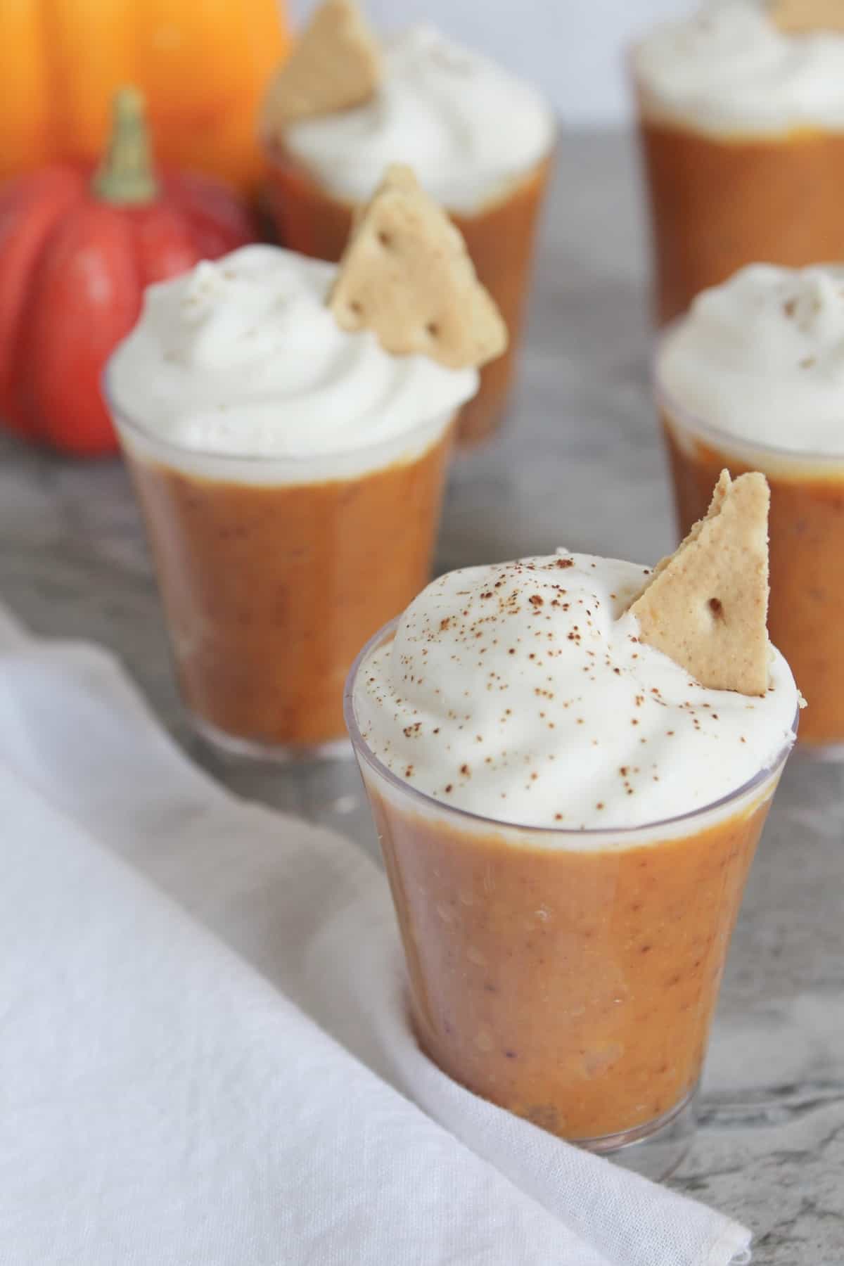 Pumpkin pudding in shot glasses topped with whipped cream.