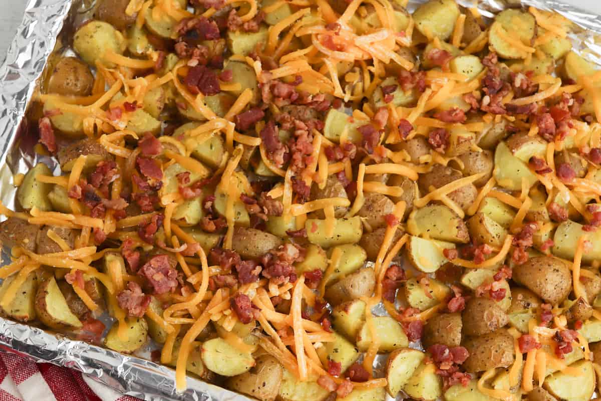 Roasted potatoes with cheese and bacon on a sheet pan.