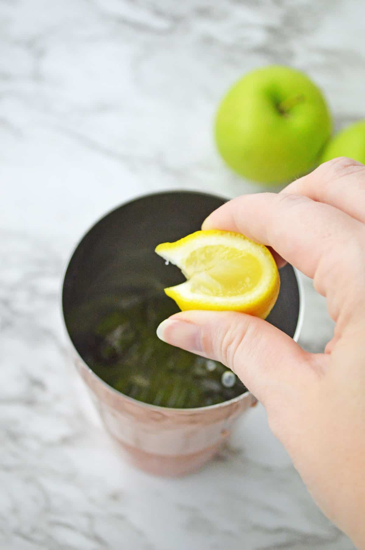Squeezing lemon into a shaker with ice.