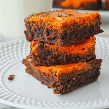 Orange brownies on a white plate.
