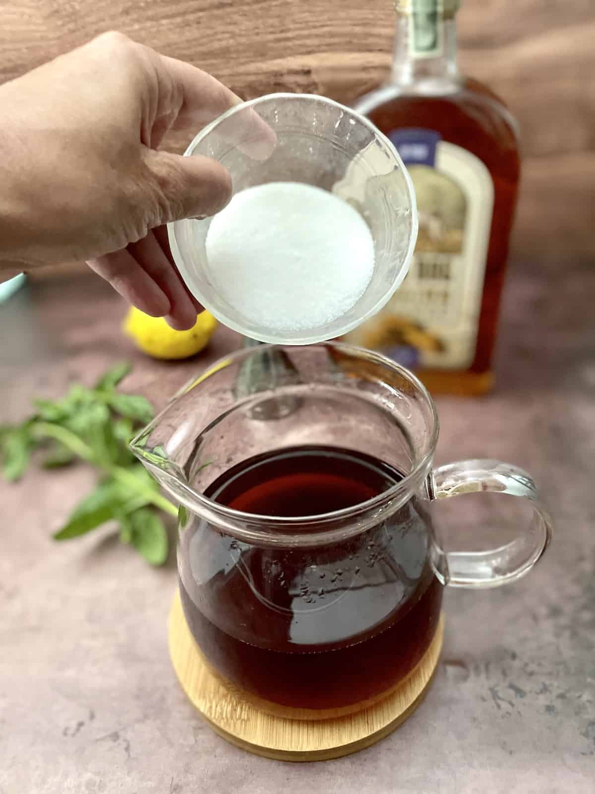 Adding sugar to pot of tea.