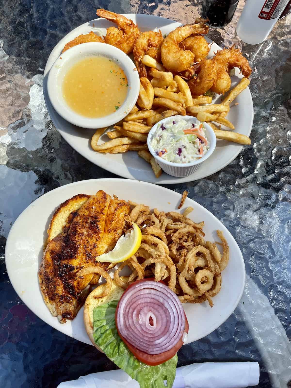 Fried shrimp with French fries and a fish sandwich with onion rings.