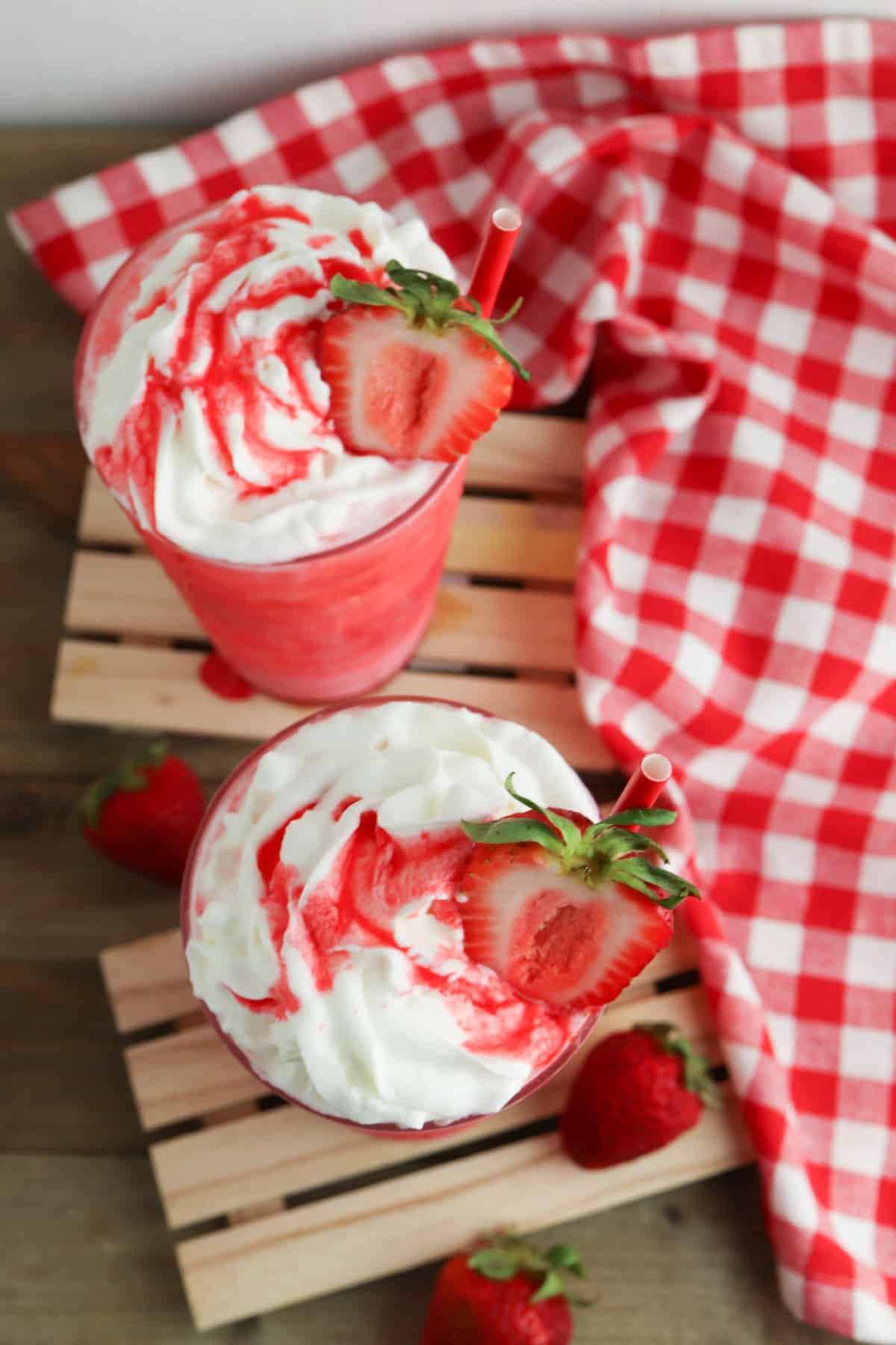 Red drink in a glass with whipped cream and strawberry.