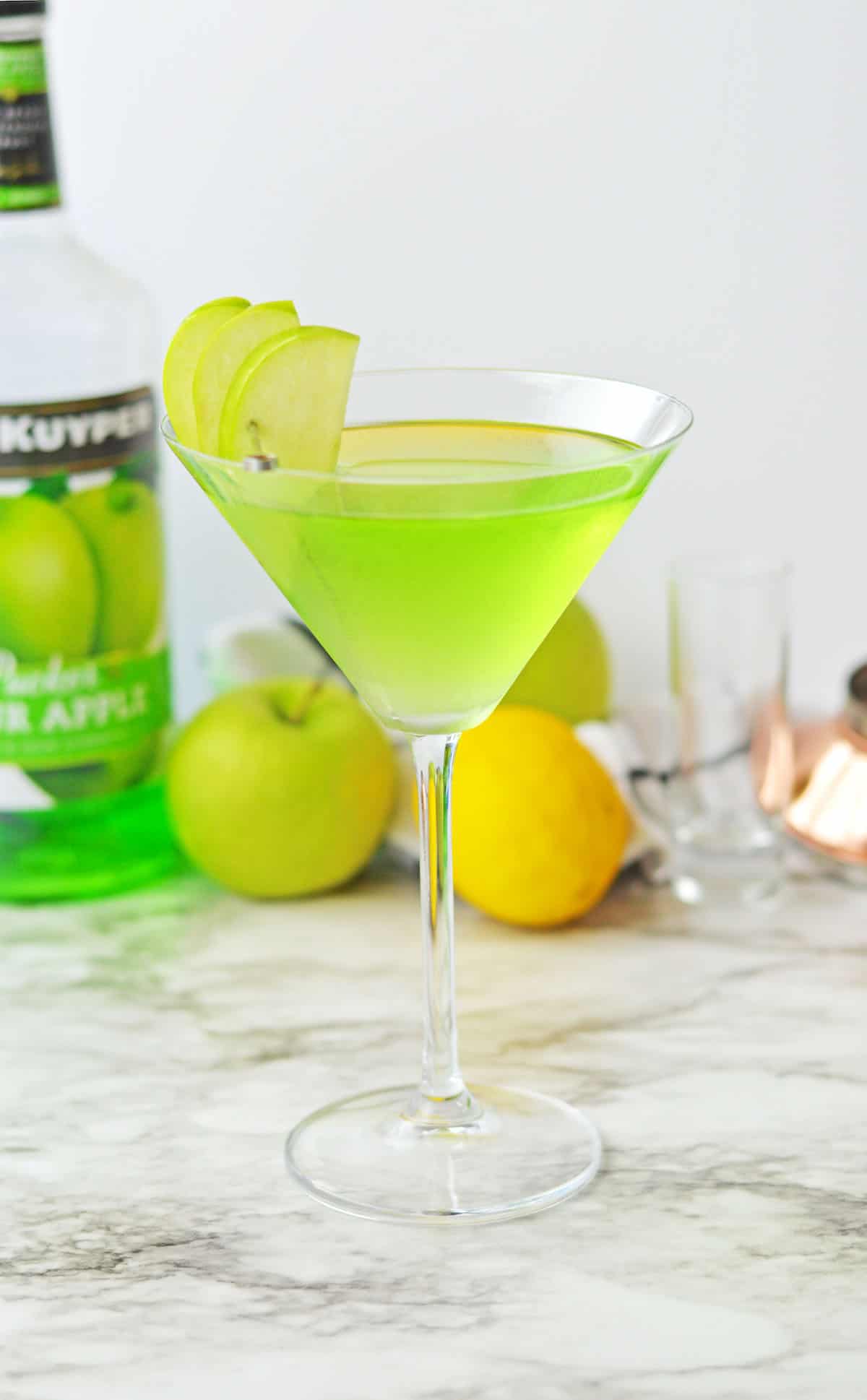 Green liquid in a martini glass with green apple slices.