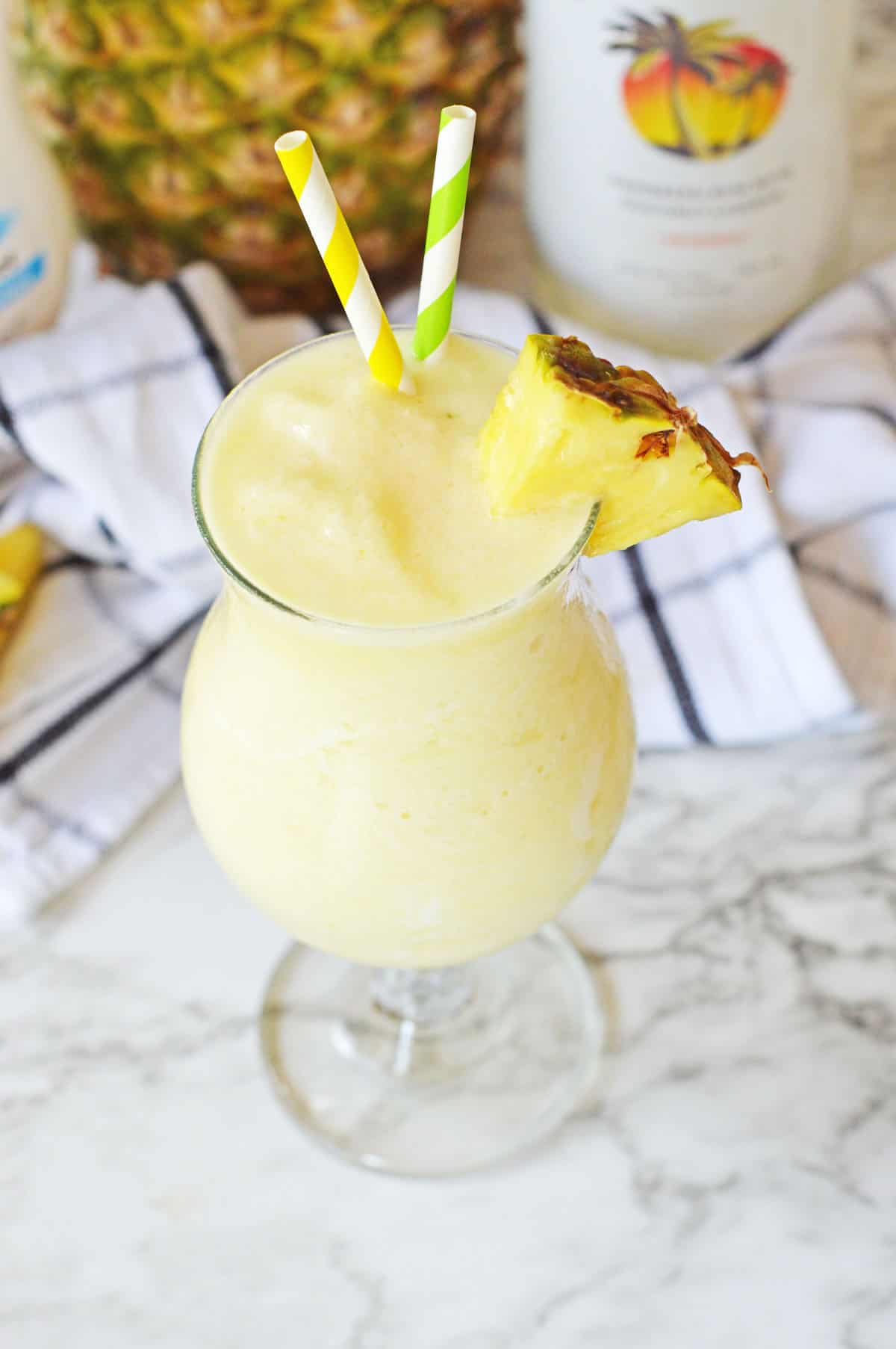 Pina colada with pineapple slice on marble table.