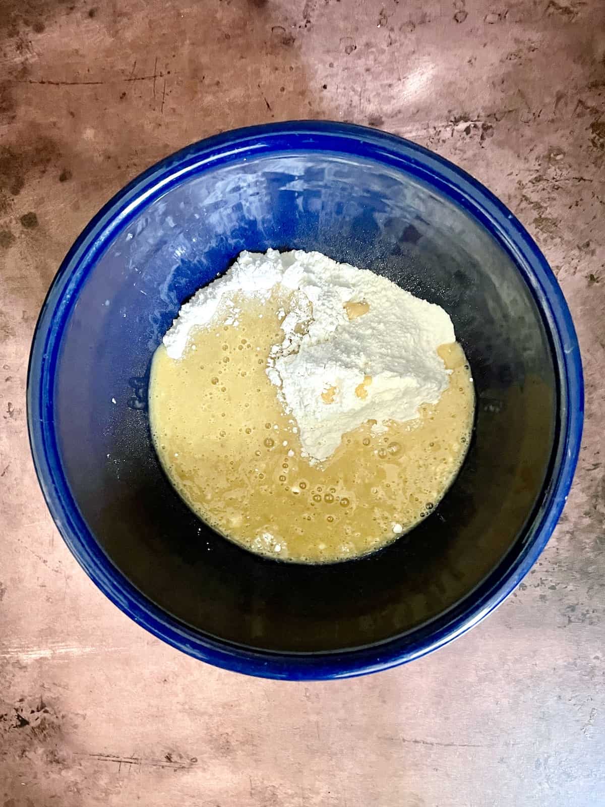 Flour with other ingredients in blue bowl.
