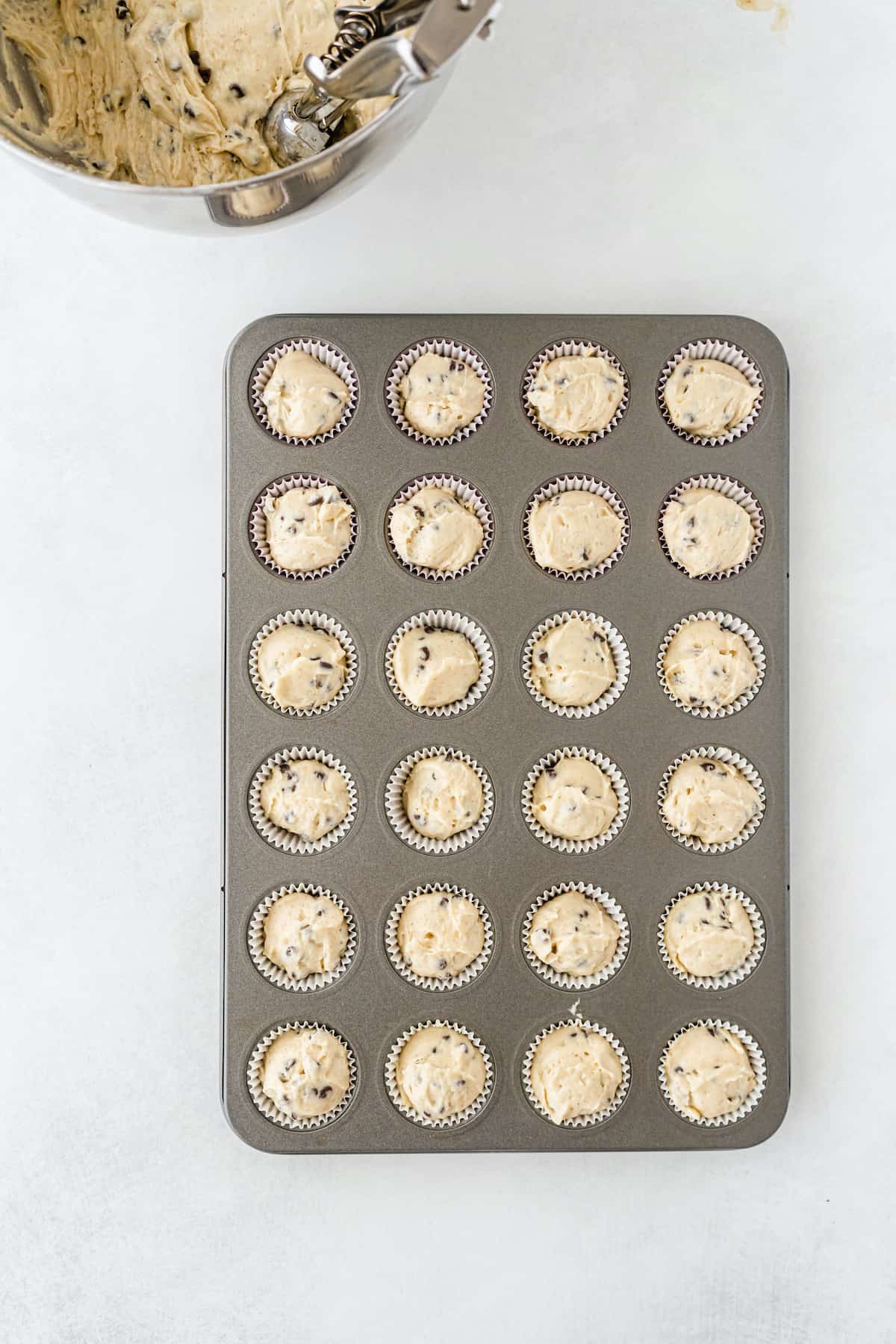 Mini chocolate chip muffin dough in tin on a white table.