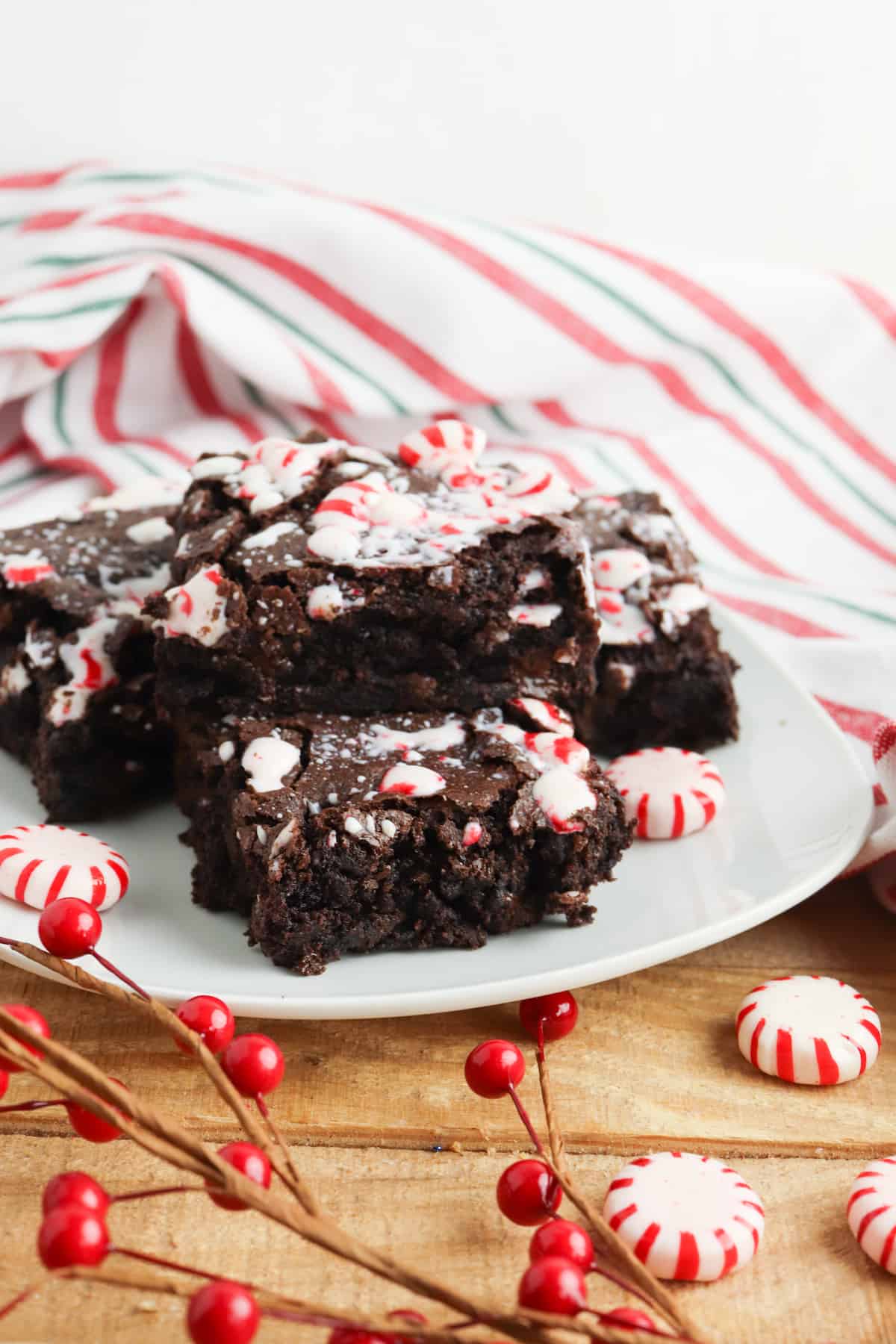 Brownies with peppermint candies on white plate on wood table. 