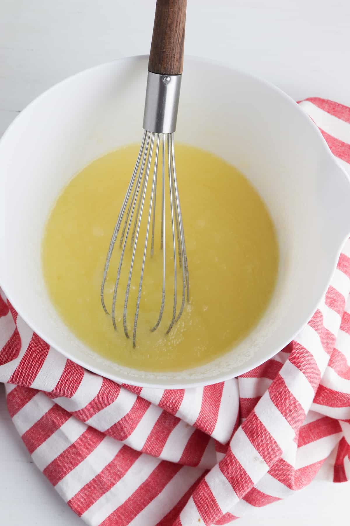 Sugar and butter blended in a white bowl with whisk.