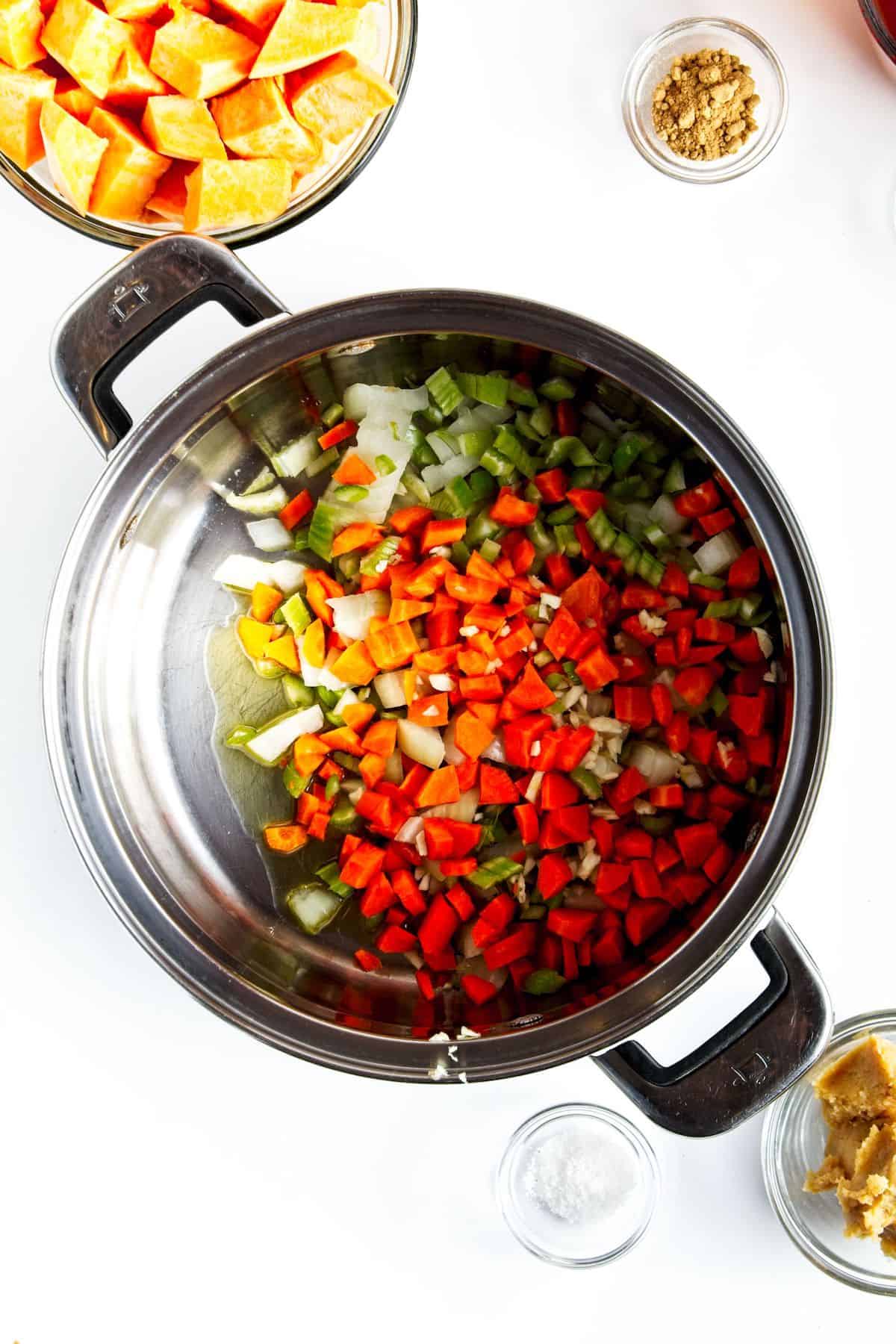 Chopped vegetables in a stock pot with oil.