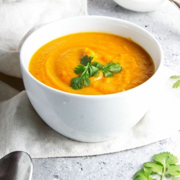 Sweet potato soup in a white bowl with parsley garnish.