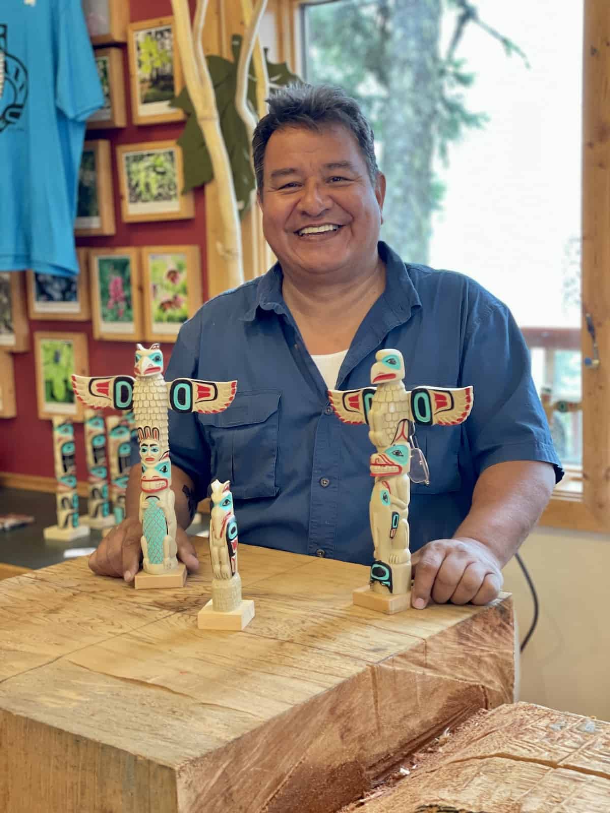 Man smiling with totem poles.