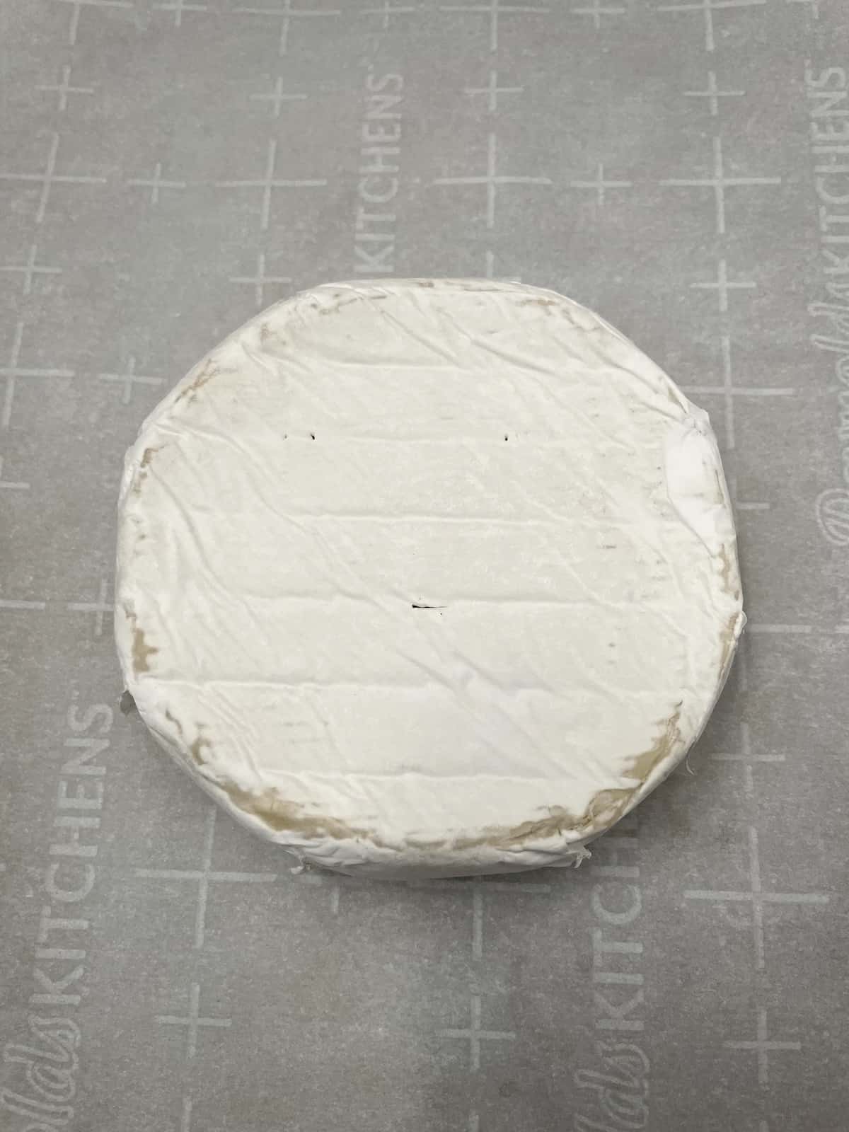 Brie cheese on parchment paper on a baking sheet.