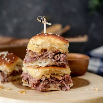 Small bun with roast beef and cheese on round tray.