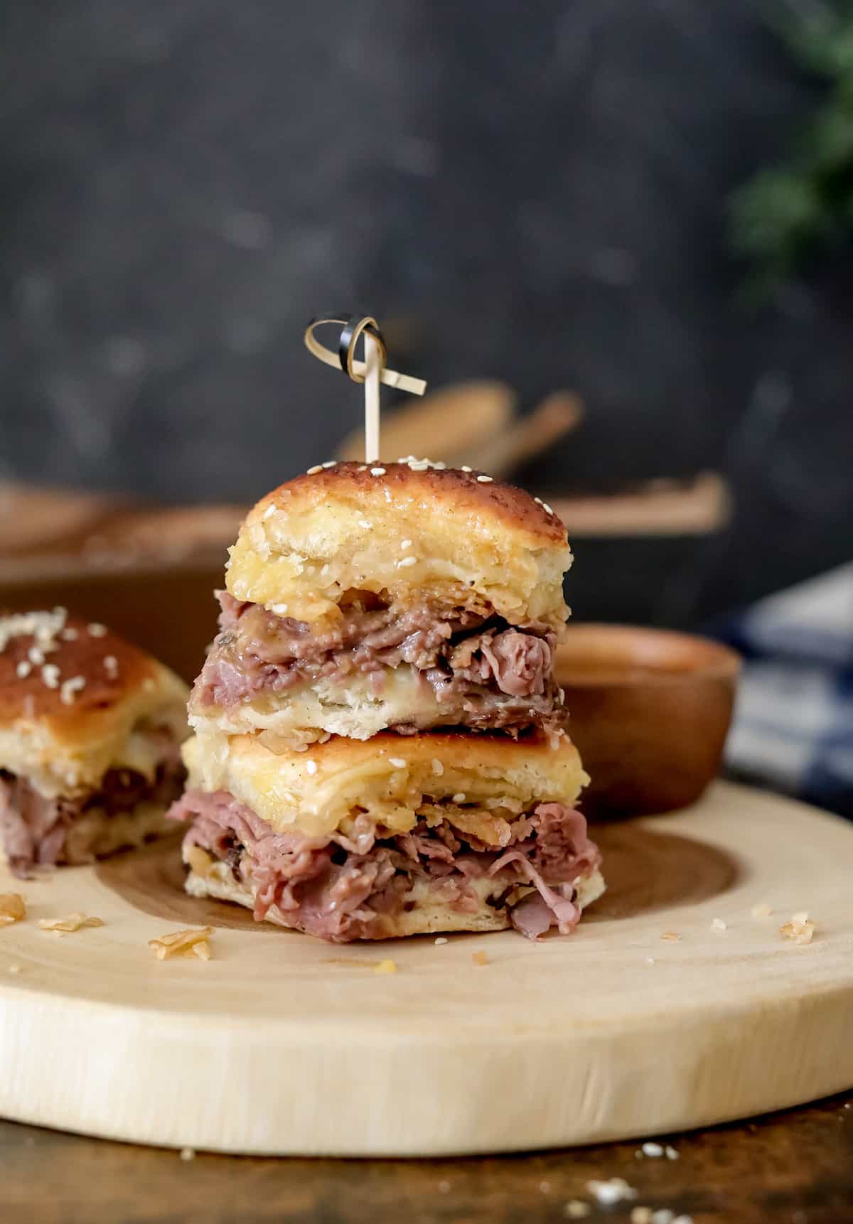 Small bun with roast beef and cheese on round tray.