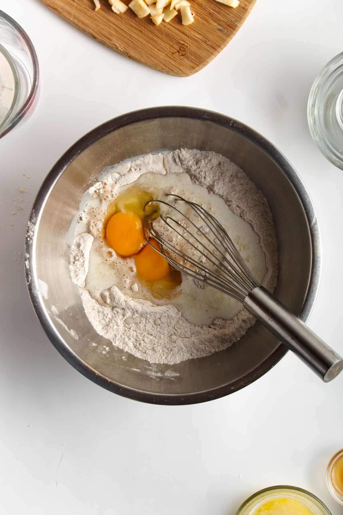 Flour, milk, and eggs in a stainless bowl.