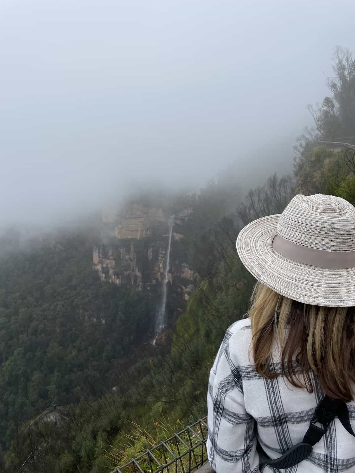 Woman in hat looking at waterfall.