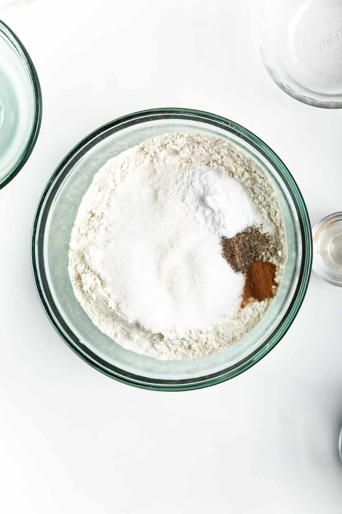 Flour and seasonings in glass bowl on white counter.