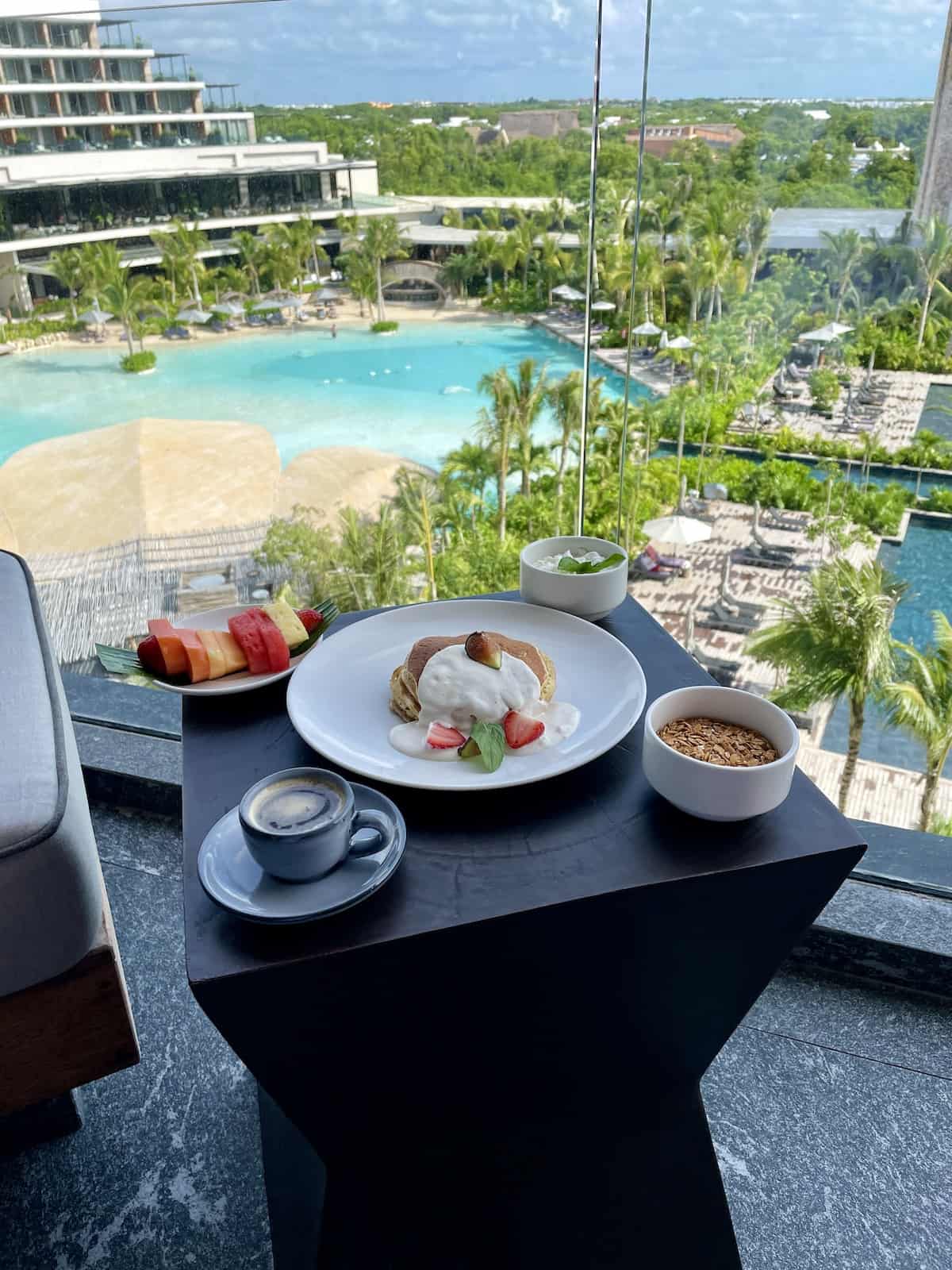 Pancakes and fruit on plate on tray on balcony.