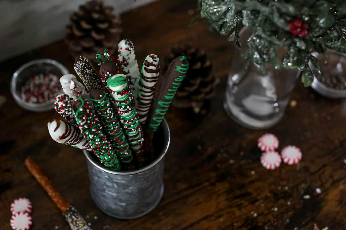 Holiday decorated chocolate covered pretzels in a silver coffee tin.