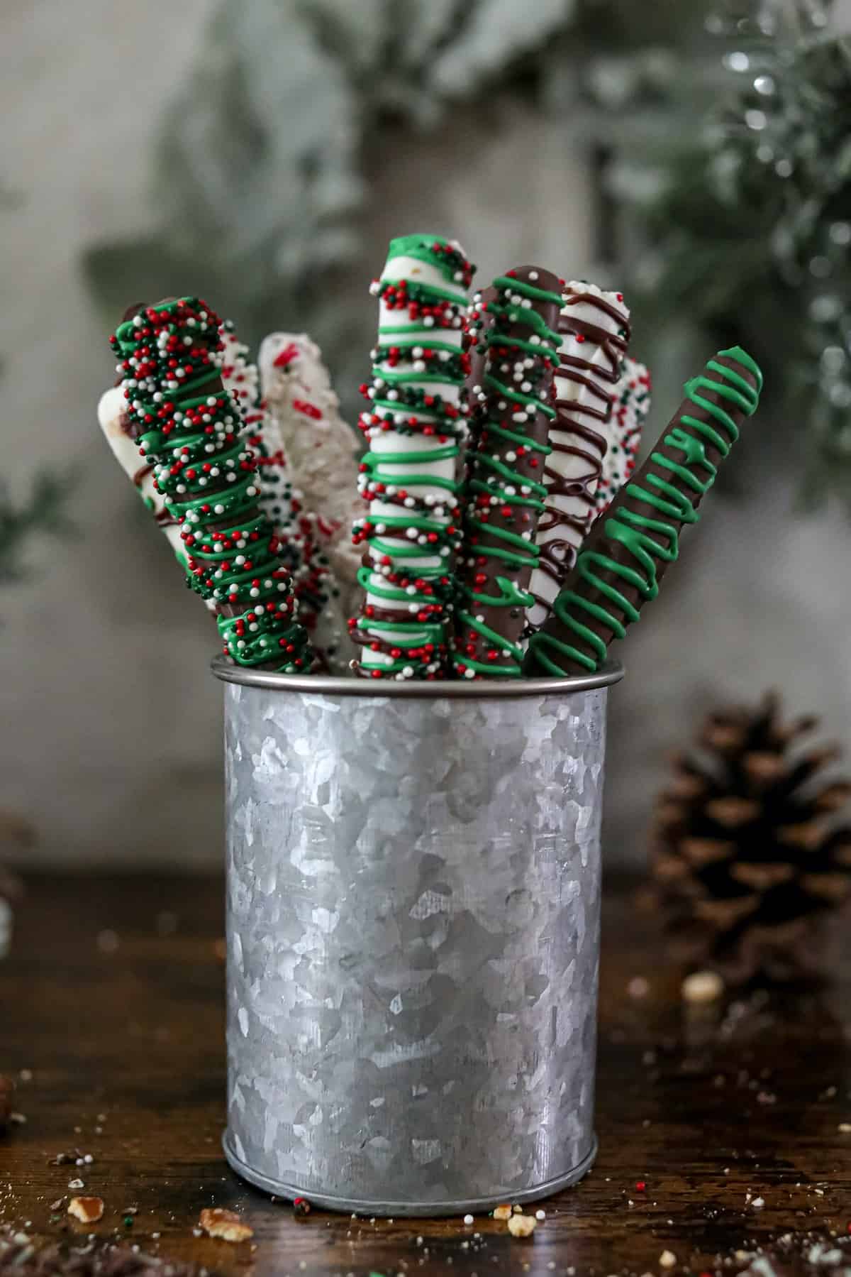 Holiday decorated chocolate covered pretzels in a silver coffee tin.