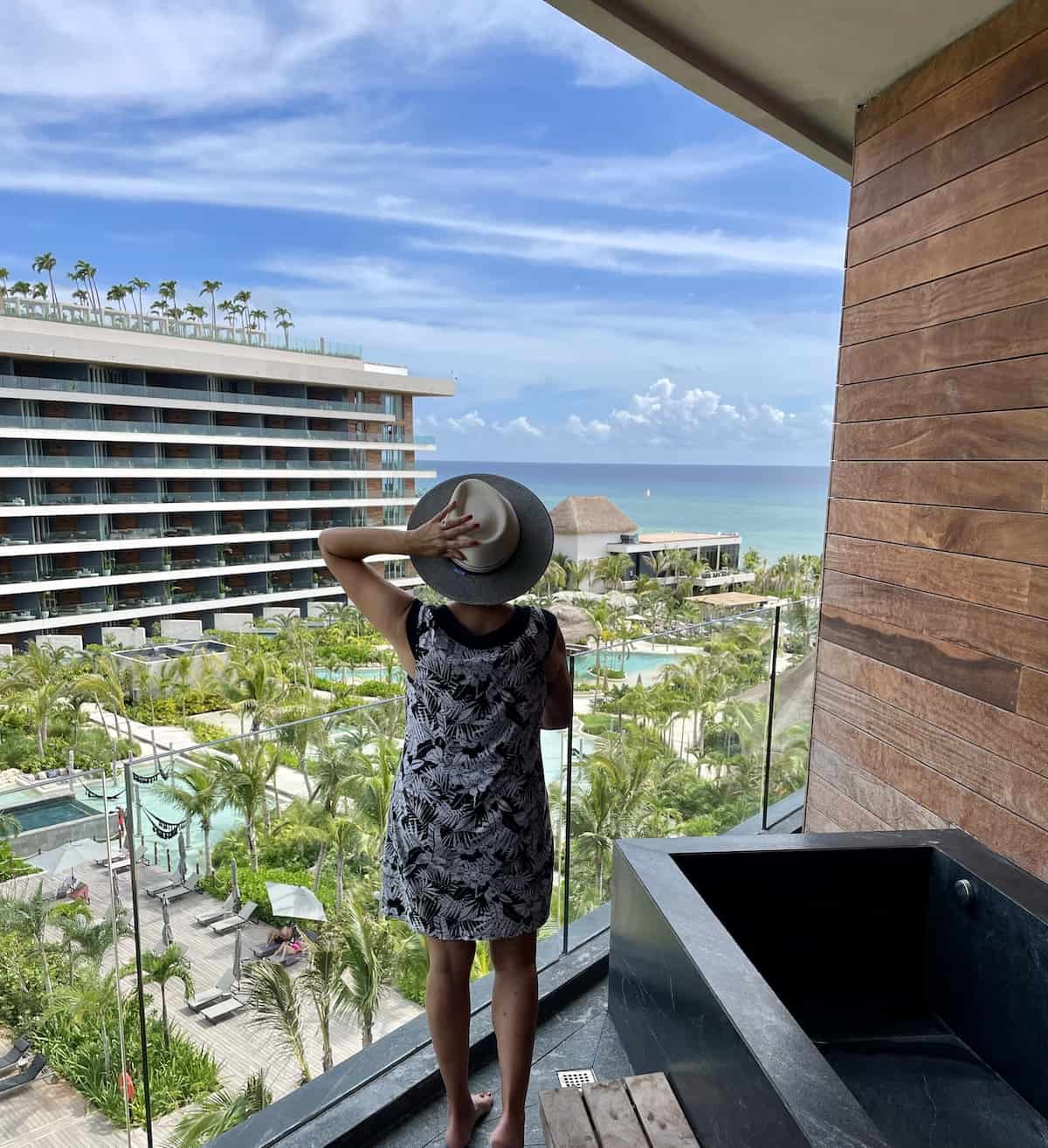 Woman on balcony looking at ocean.