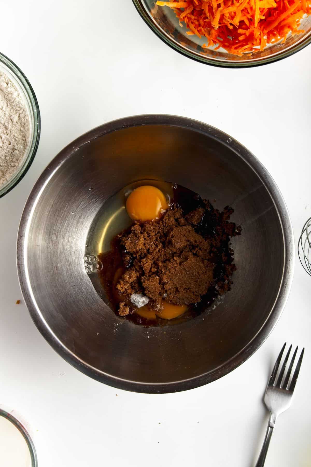 Eggs and brown sugar in a stainless bowl.