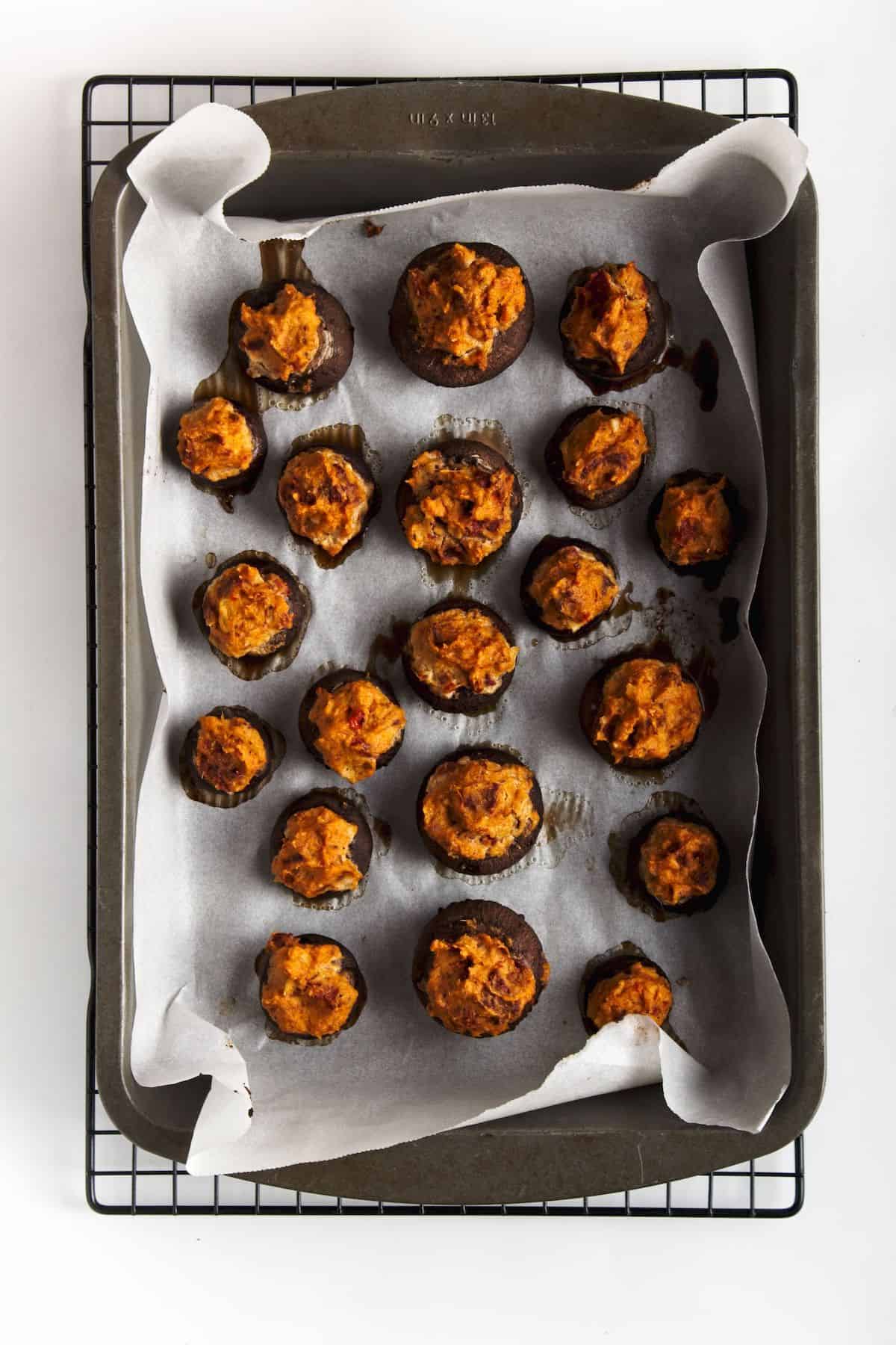 stuffed mushrooms on parchment on a baking sheet.