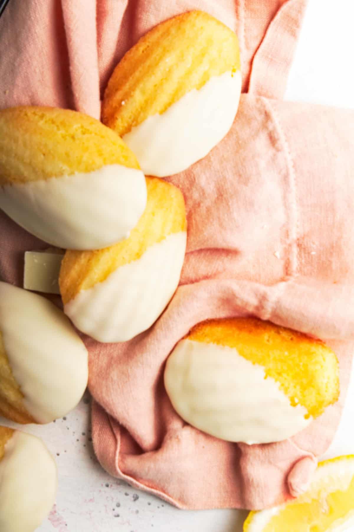 White chocolate dipped madeleines on a pink napkin.