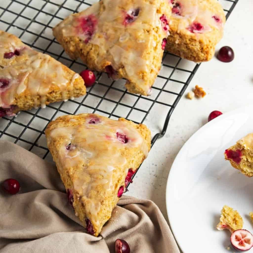 Scones with icing on a wire rack with taupe napkin.