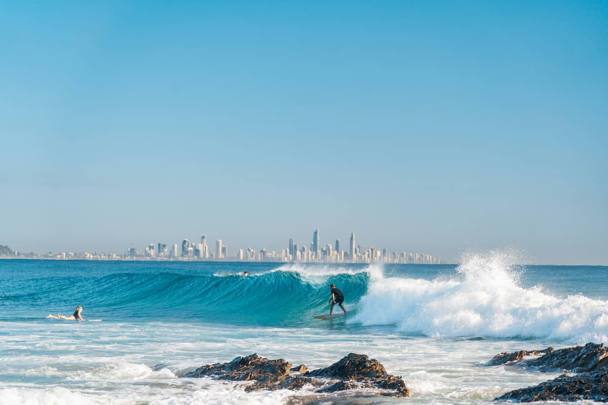 Surfer with city in background.