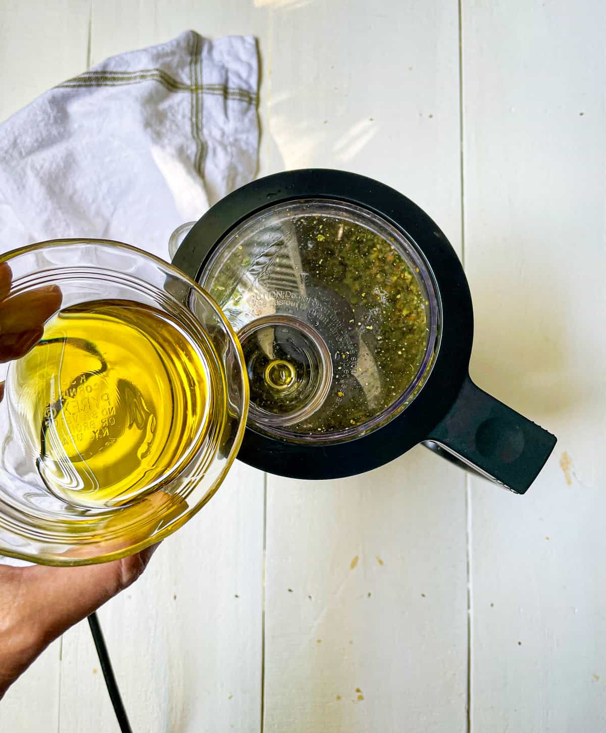 Ingredients to make pistachio pesto blended in a food processor with olive to drizzle into the mix..