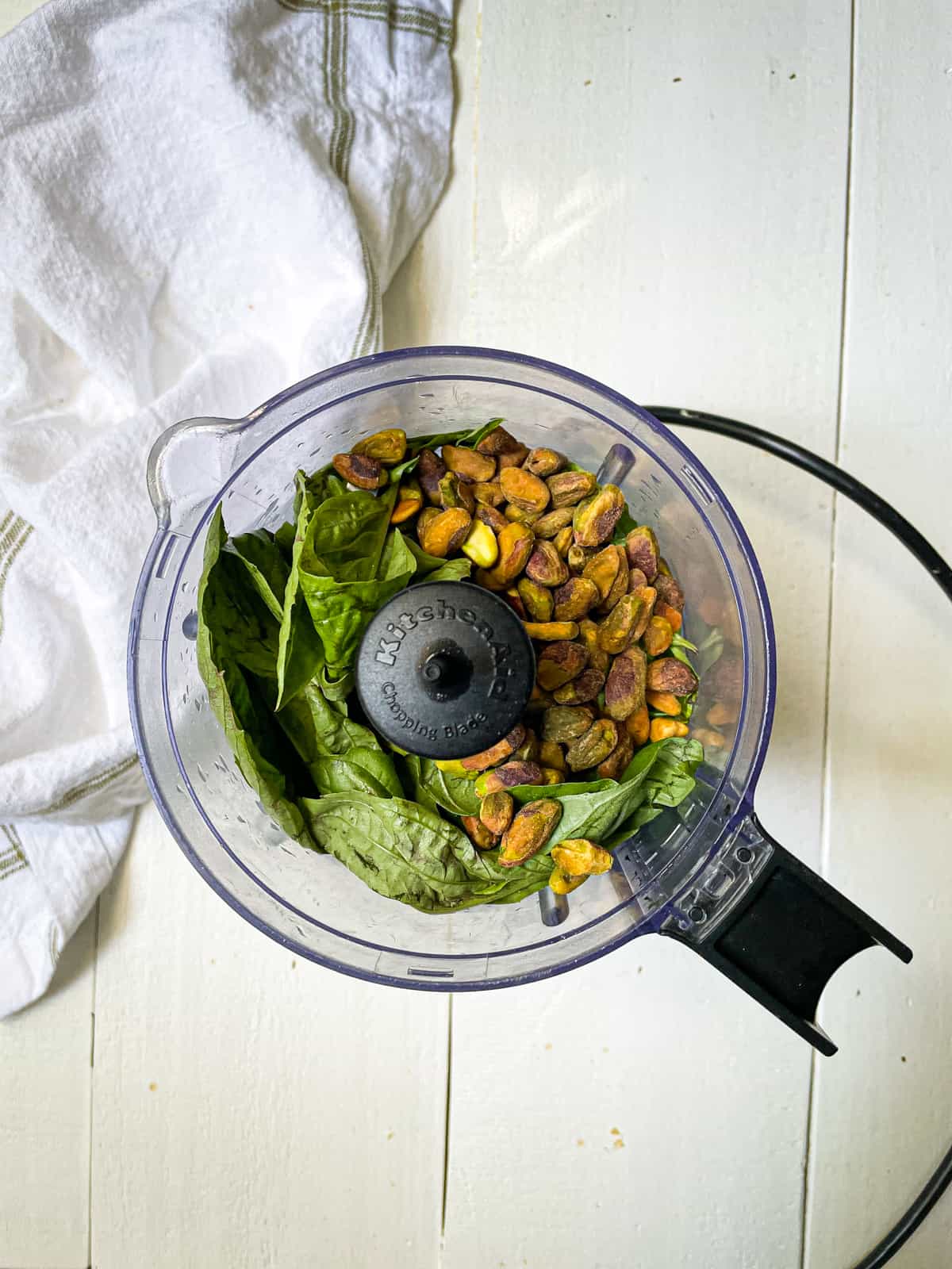 Ingredients to make pistachio pesto in a food processor.