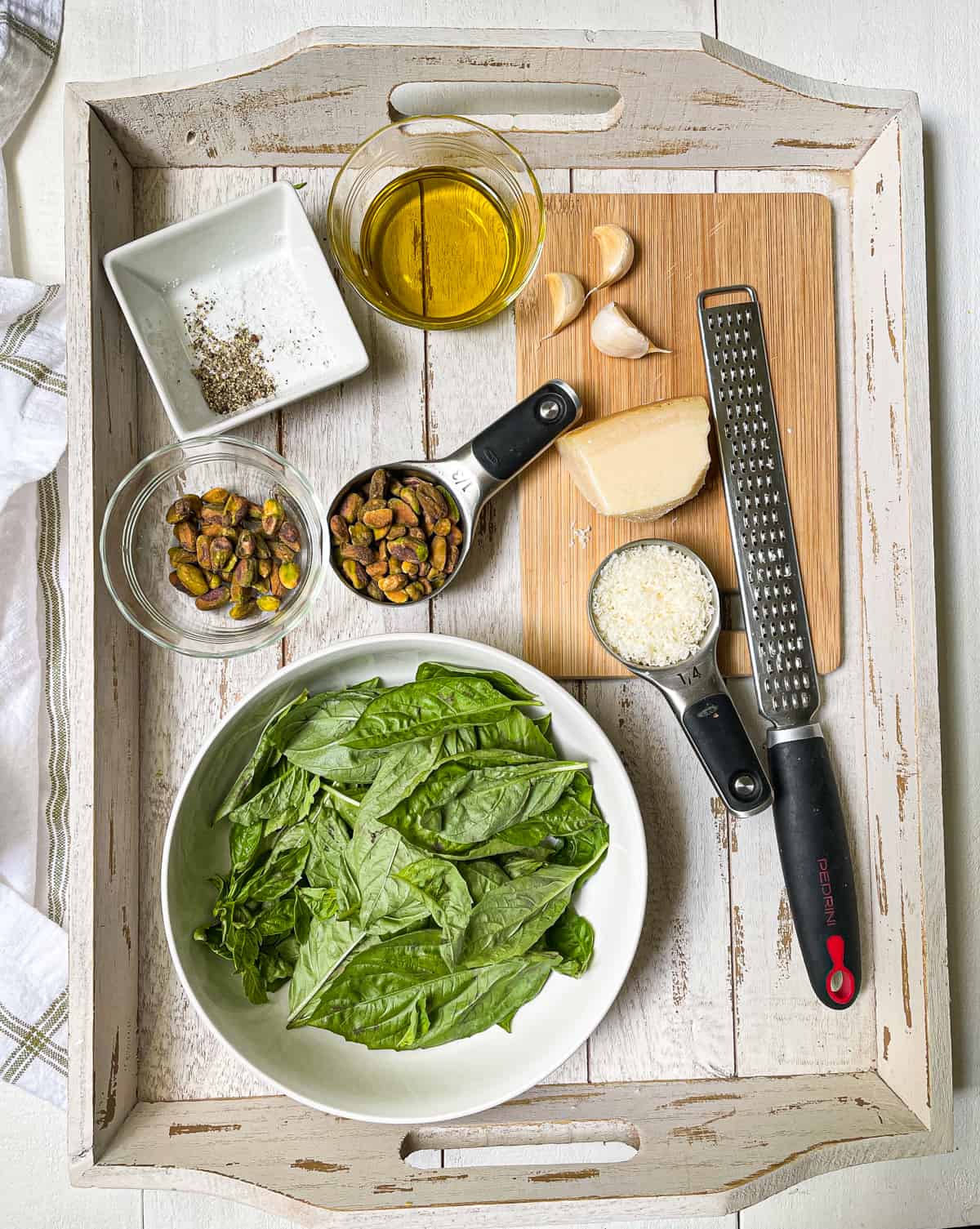 Ingredients to make pistachio pesto on a white tray.