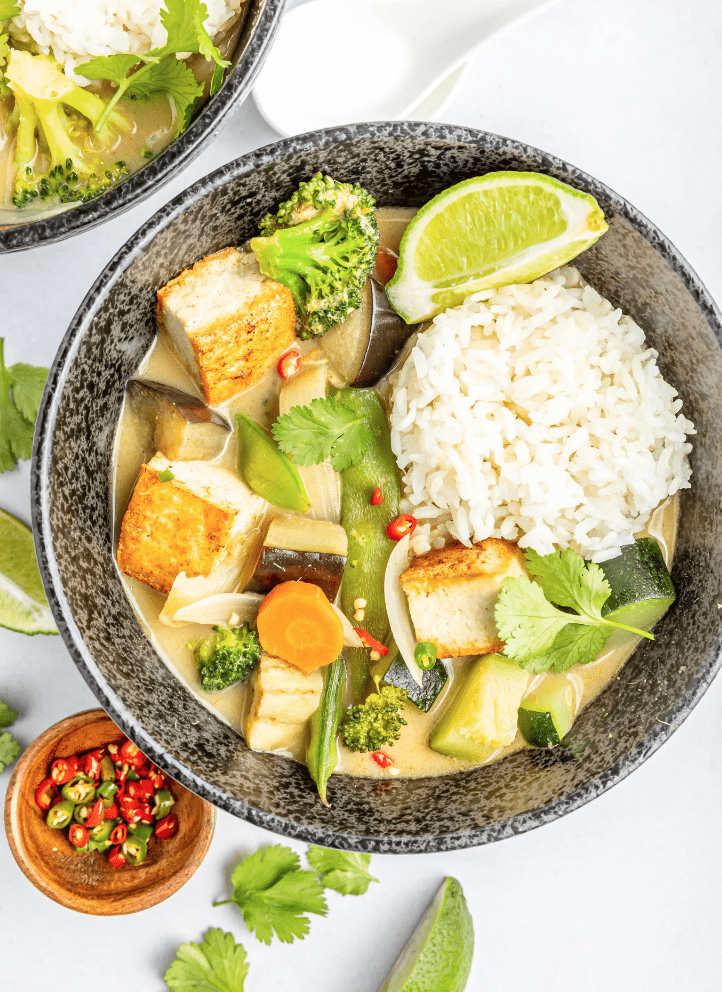 Thai green curry in a grey dish with lime.