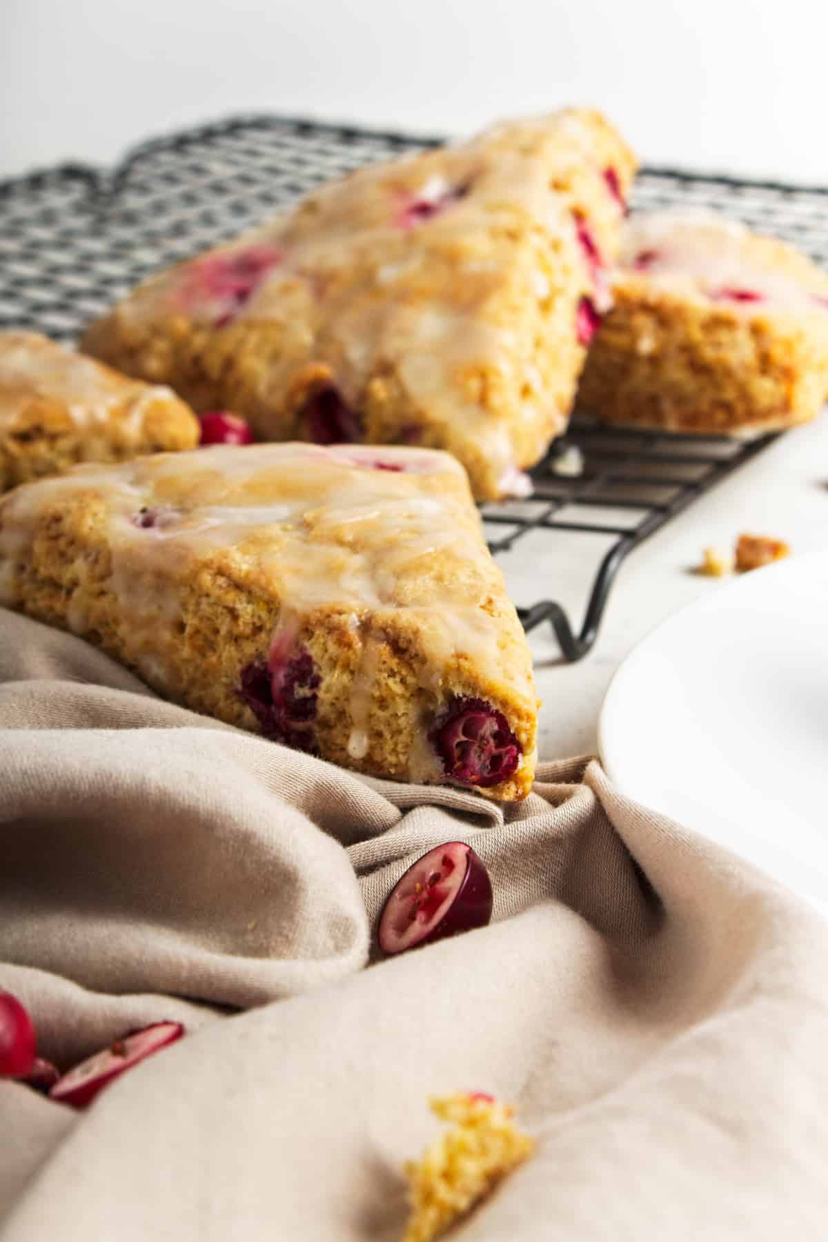 Cranberry orange scones with icing on a wire rack.