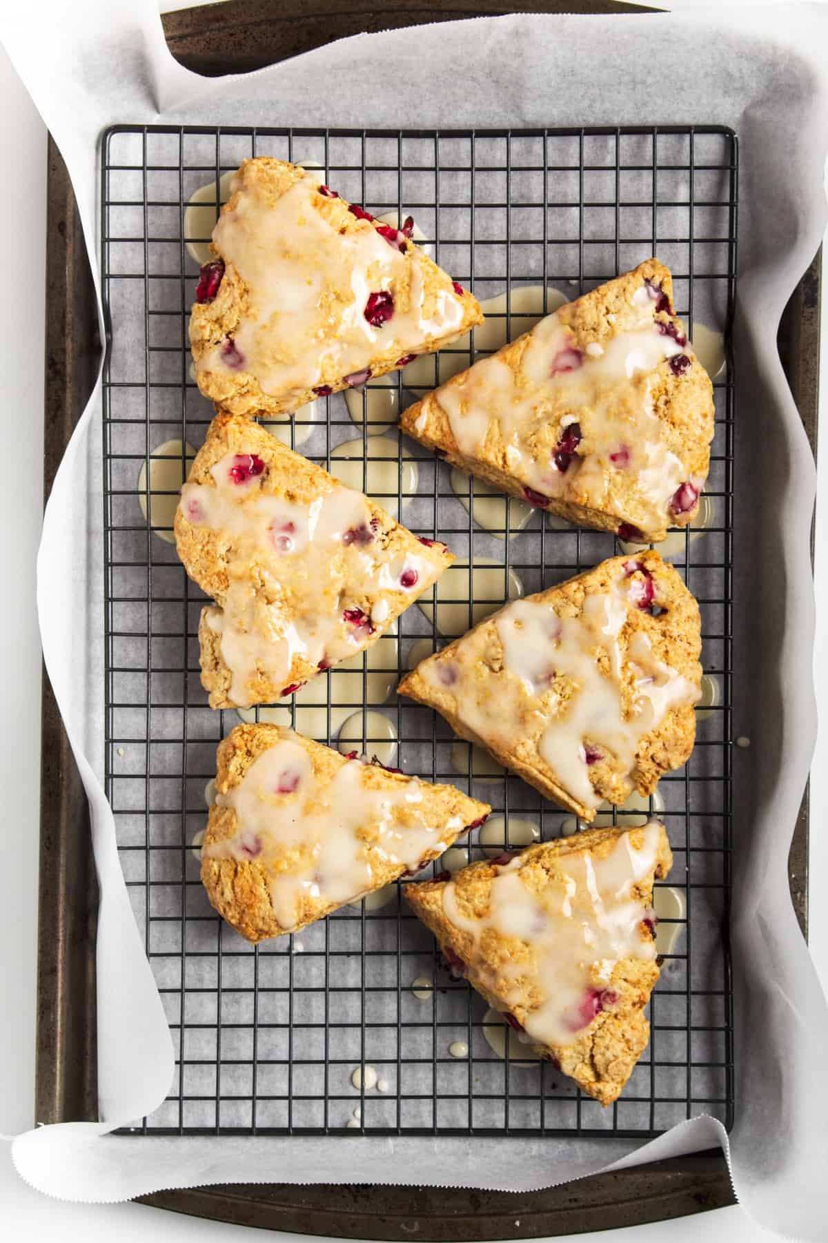 Cranberry orange scones with icing on a wire rack.