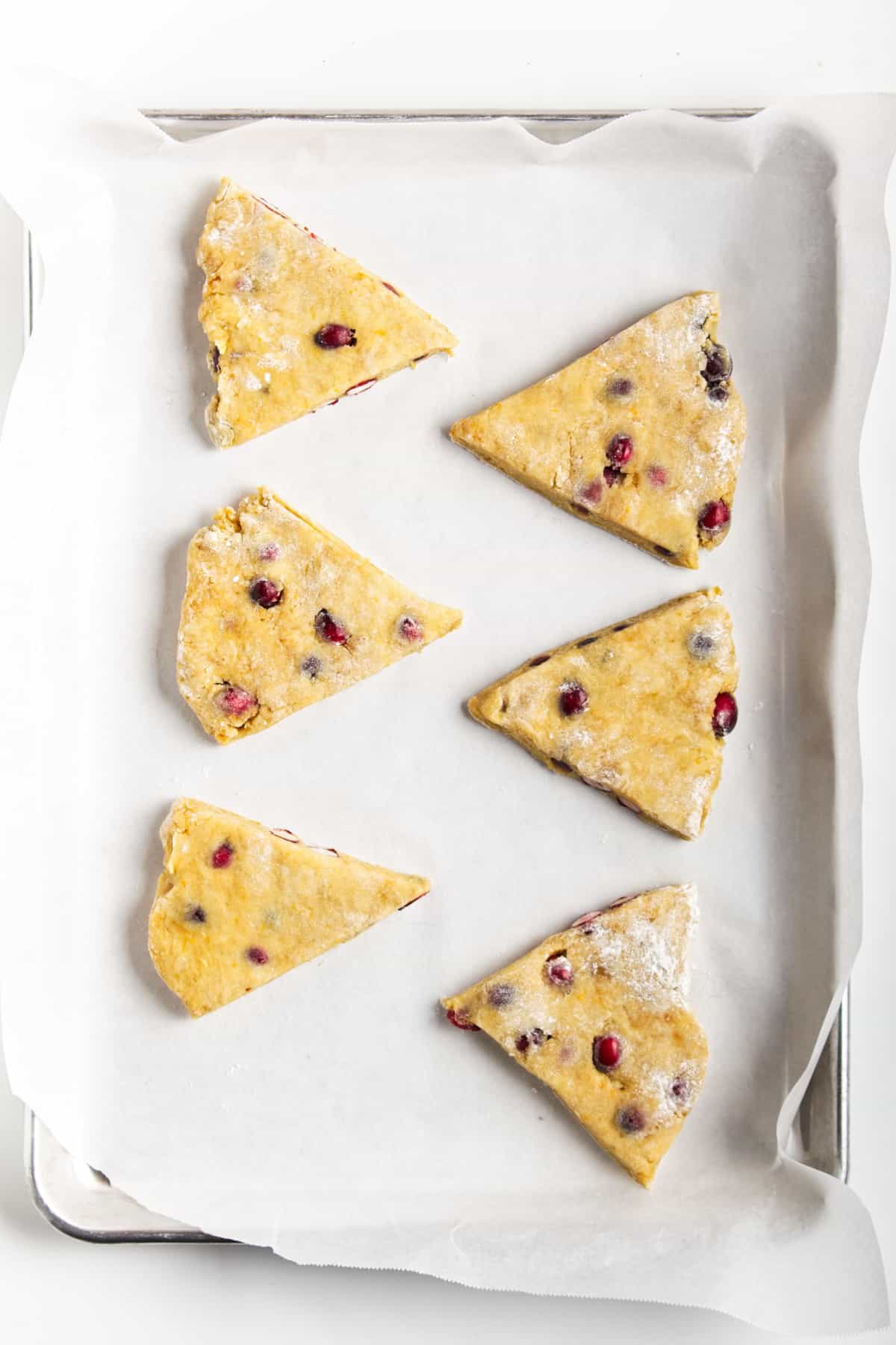 Unbaked cranberry orange scones with icing on a wire rack.