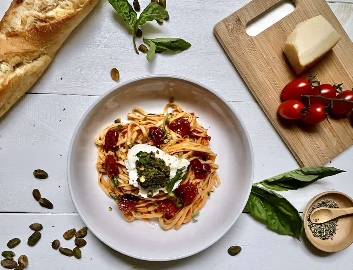 Pasta in a bowl with roasted grape tomatoes and basil.