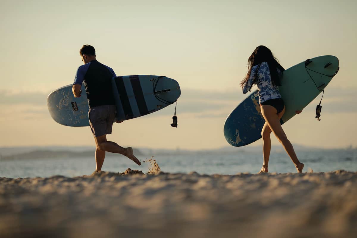 Two surfers walking toward ocean.