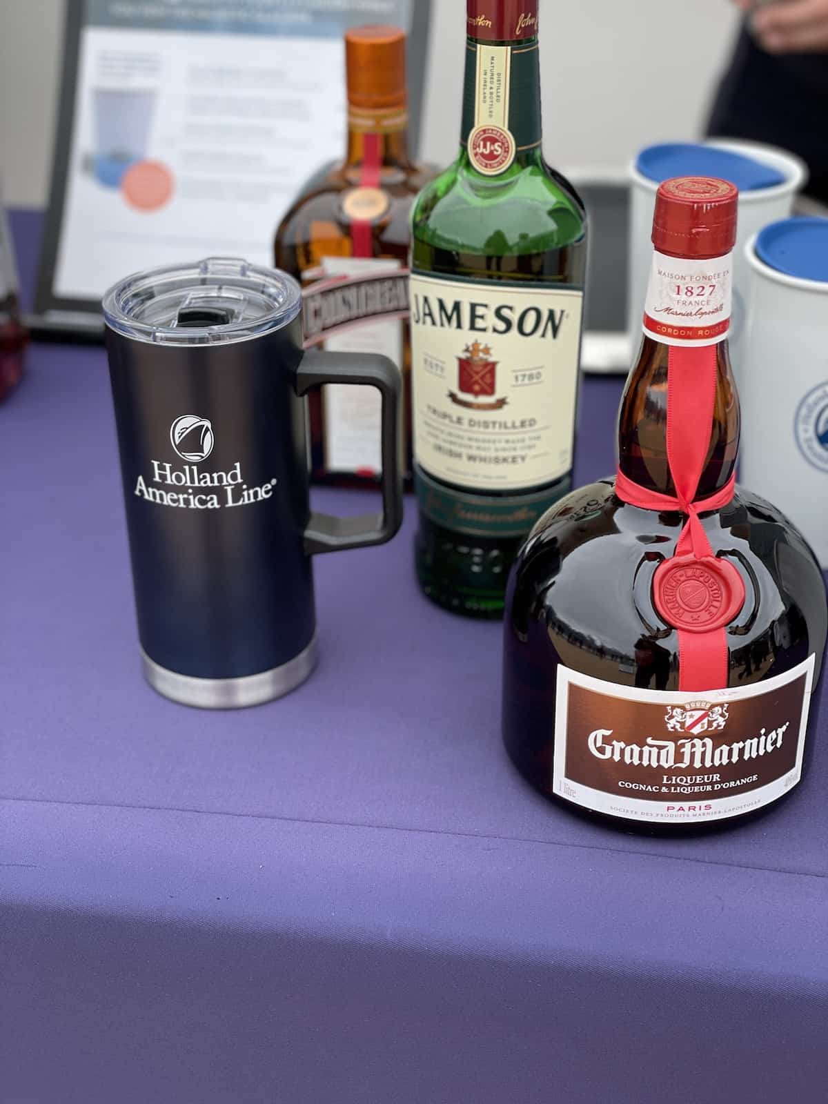 Bottles of liqueurs to serve with coffee or hot chocolate on a purple tablecloth.