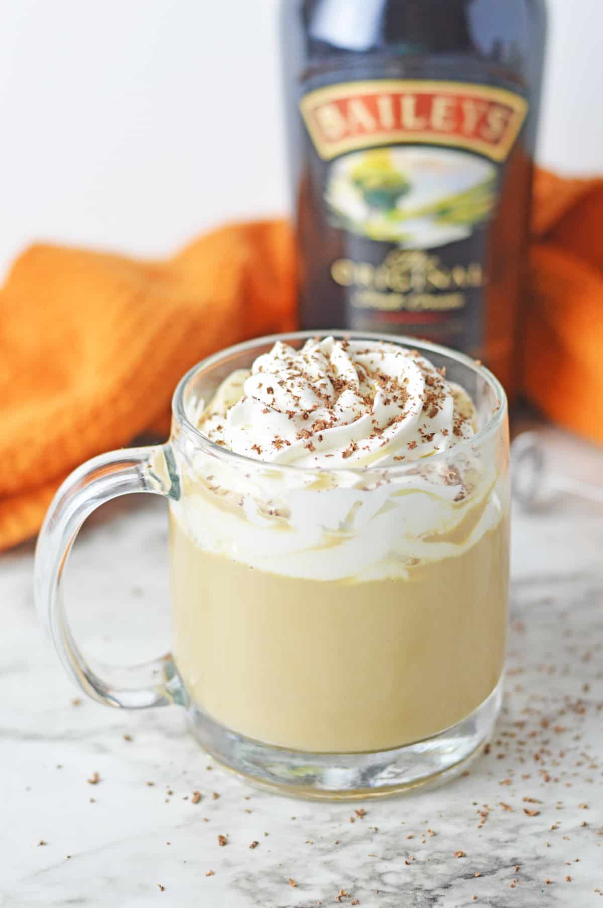 Baileys latte with whipped cream in a glass mug.