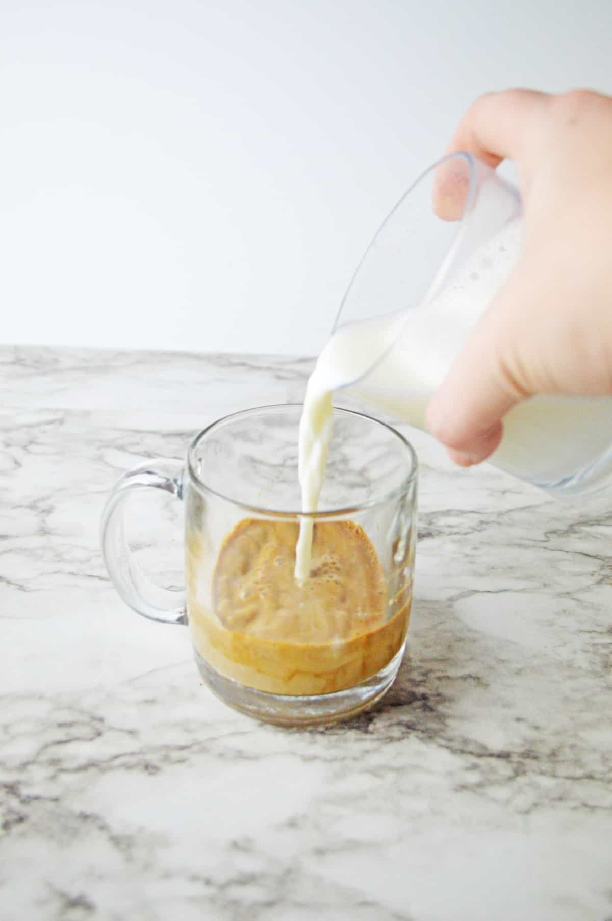 Baileys and espresso with milk in a glass mug.