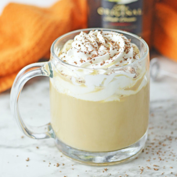 Baileys latte in a glass mug with whipped cream.