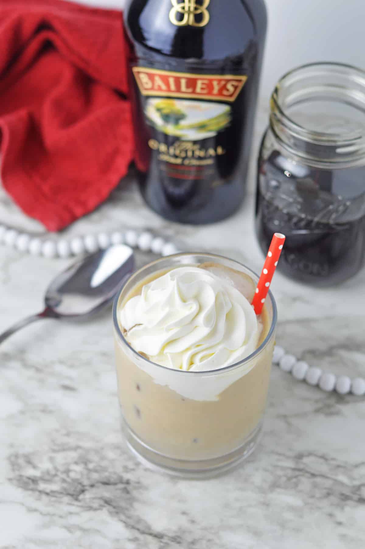 Baileys Iced Coffee in a glass with a red straw.