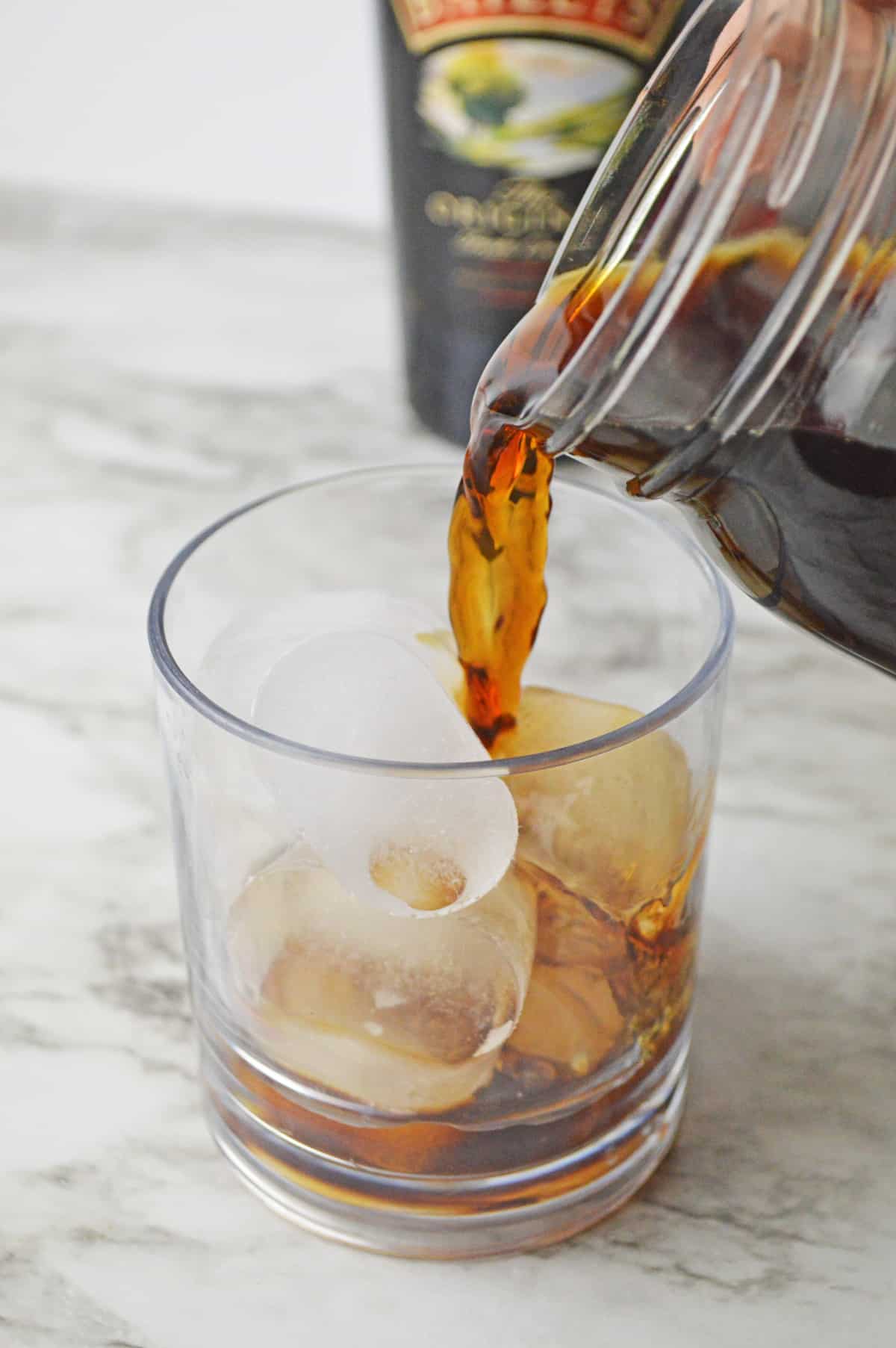 Coffee being poured into a glass over ice.